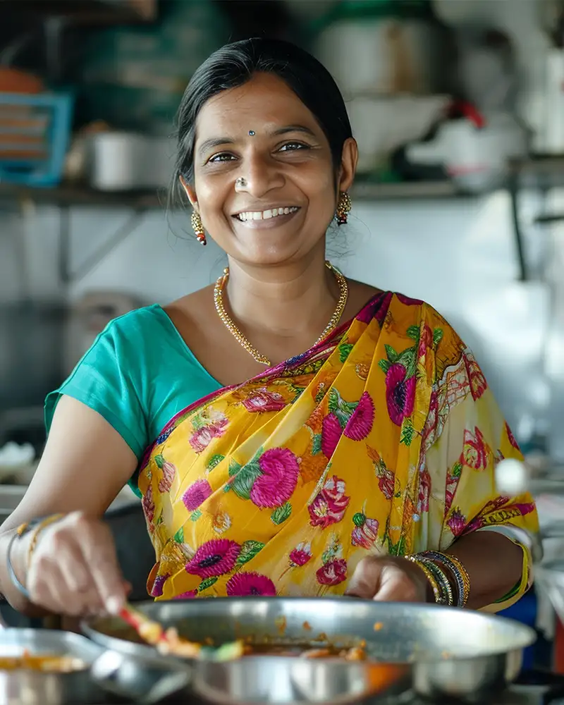 Indische Frau im Sari steht in der Küche und kocht ein Gericht
